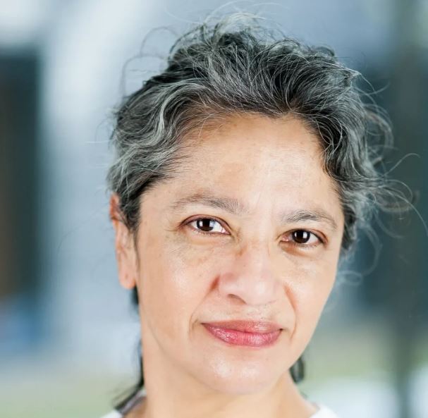 Portrett Leslie Eide, kvinne med håret satt opp og kledd i hvit helsepersonelluniform.