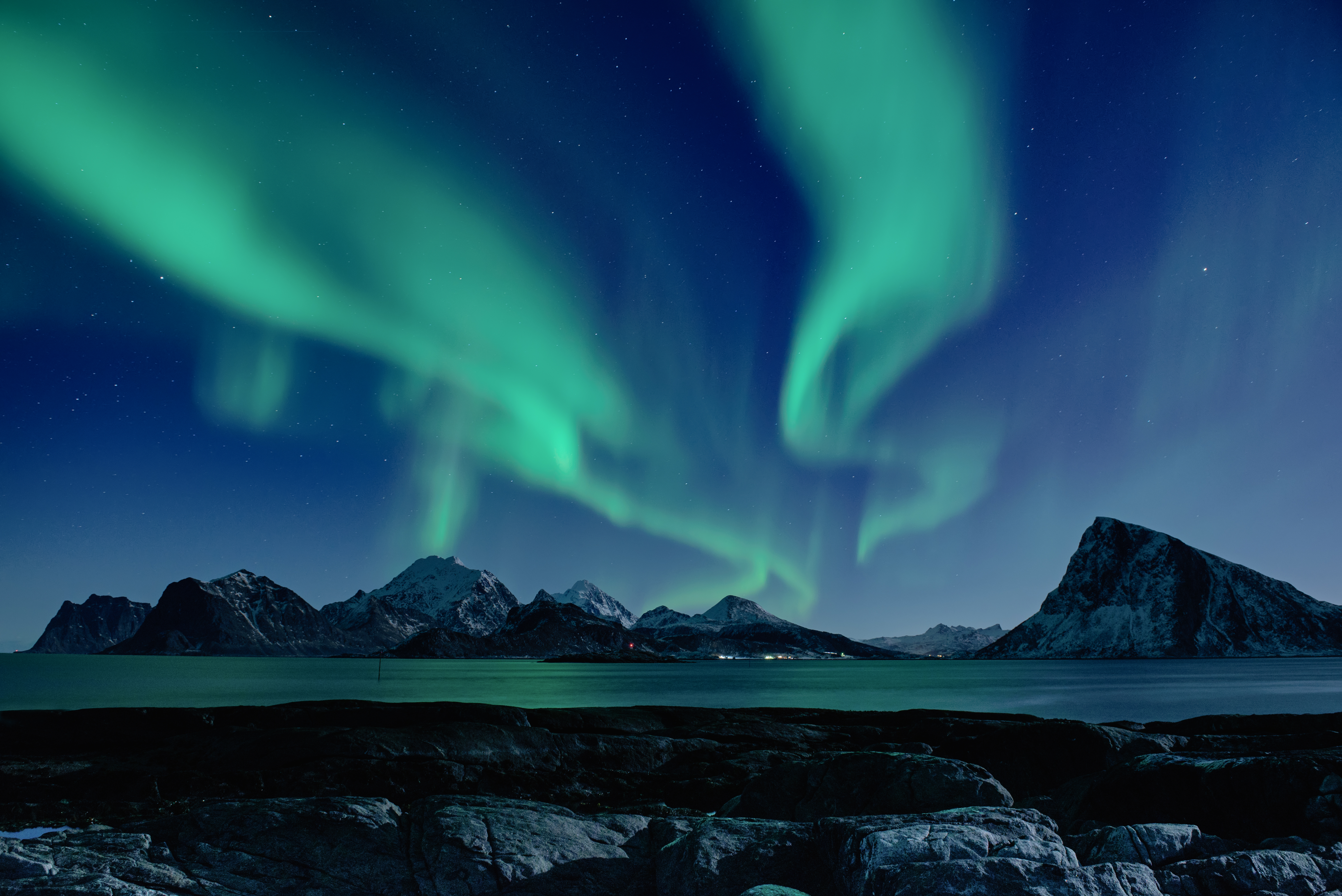 Northern lights in the night over the Lofoten islands in Northern Norway, with snow on the mountain tops.