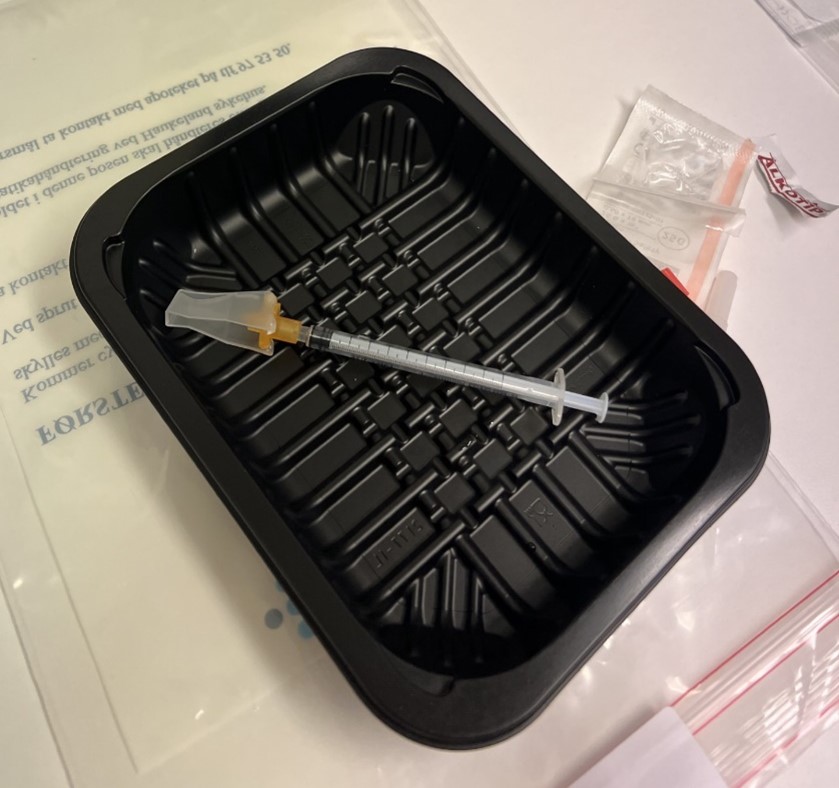 En sprøyte som ligger i en sort eske.