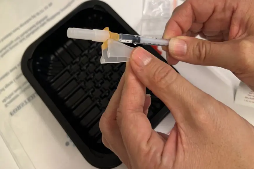 Nærbilde av en person som setter kanylespissen på sprøyten