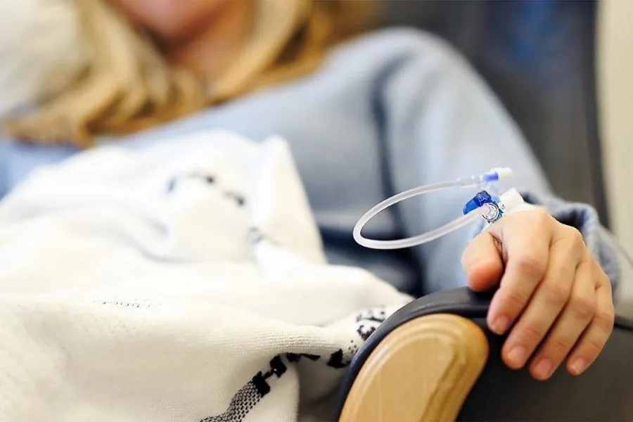 En person med en veneflon med slange koblet til hånden