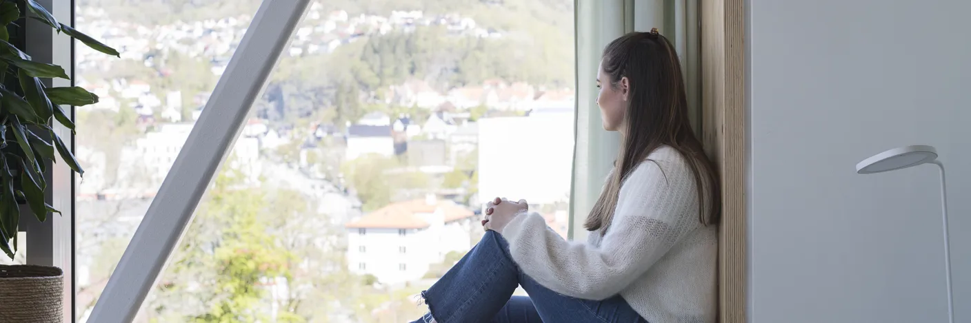 Pasient sitter i vinduskarmen