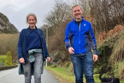 En mann og kvinne som går på en sti med trær og busker