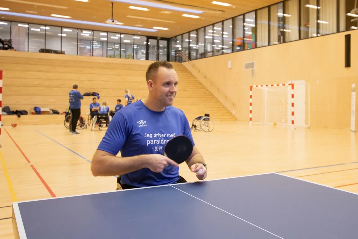 En mann i rullestol som holder en bordtennisracket