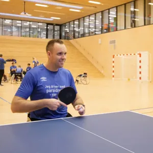 En mann i rullestol som holder en bordtennisracket