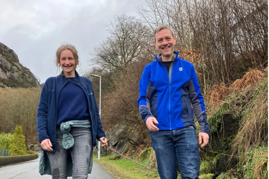 En mann og kvinne som går tur med en hund på en sti