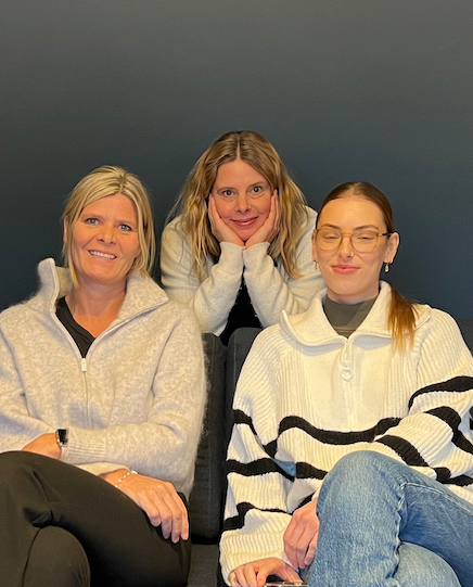 En gruppe kvinner som sitter sammen og smiler