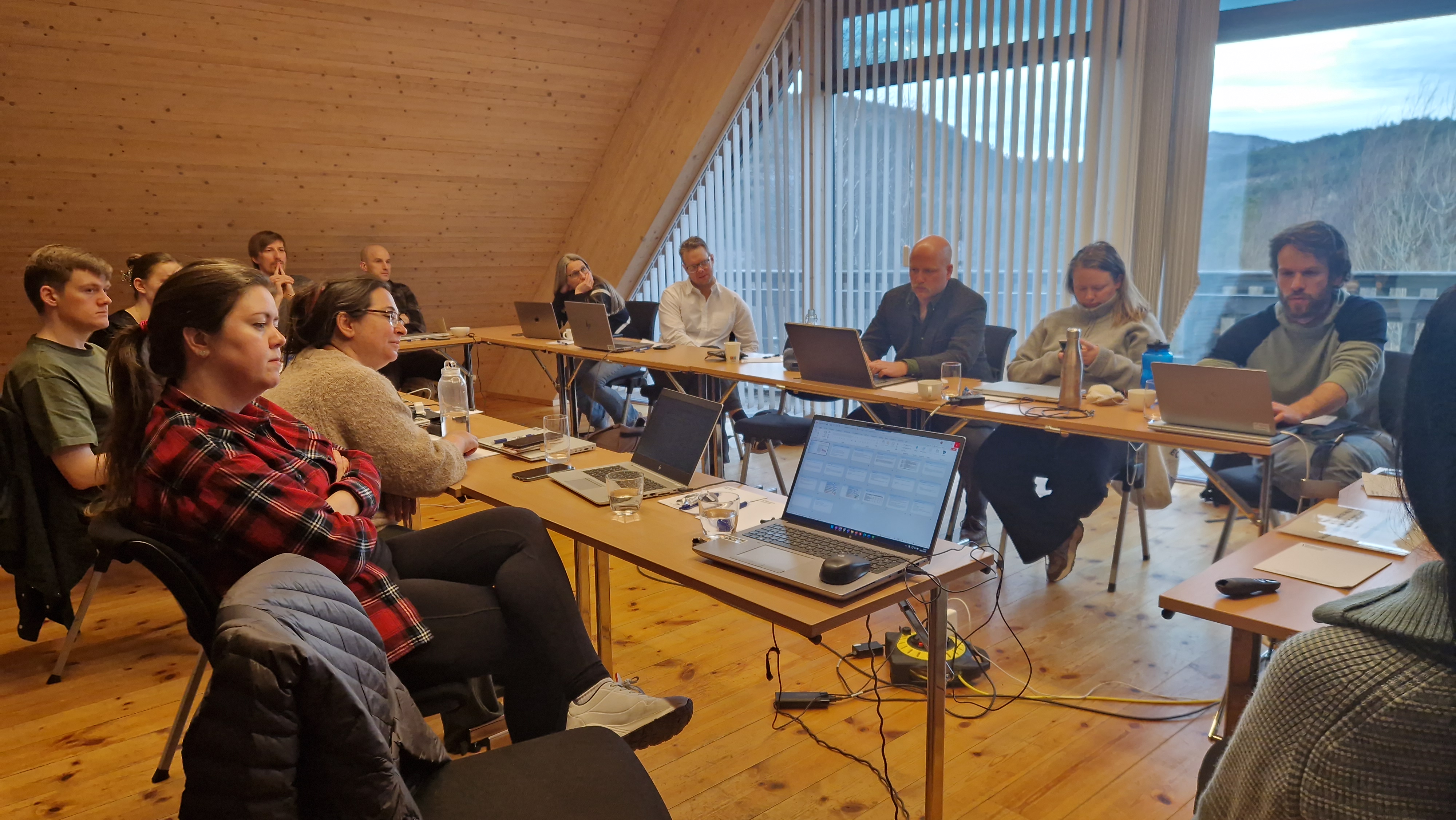 En gruppe mennesker som sitter rundt et bord med bærbare datamaskiner