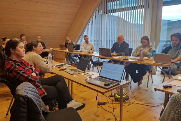 En gruppe mennesker som sitter rundt et bord med bærbare datamaskiner