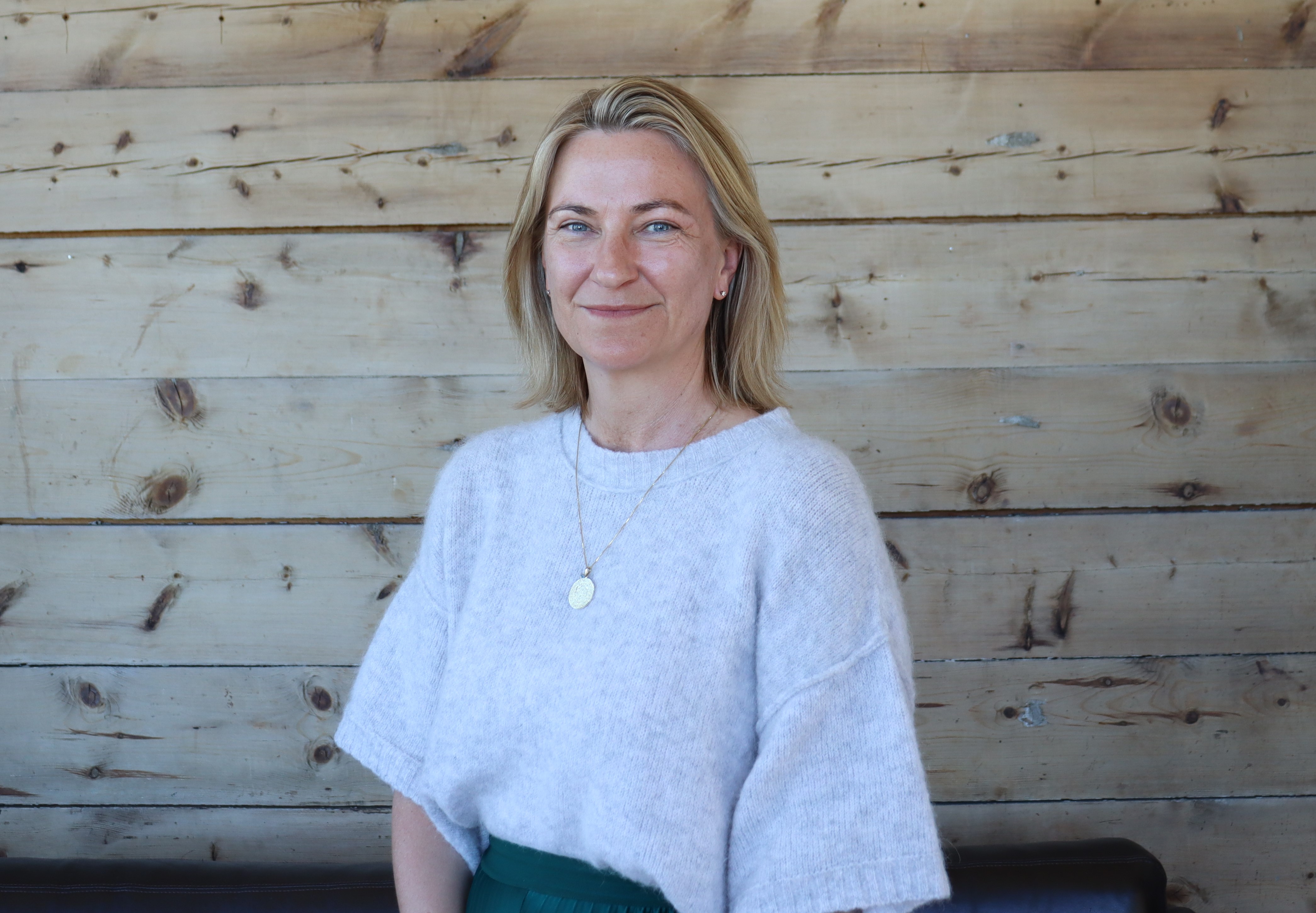 En kvinne som sitter foran en trevegg