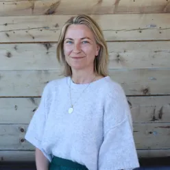 En kvinne som sitter foran en trevegg