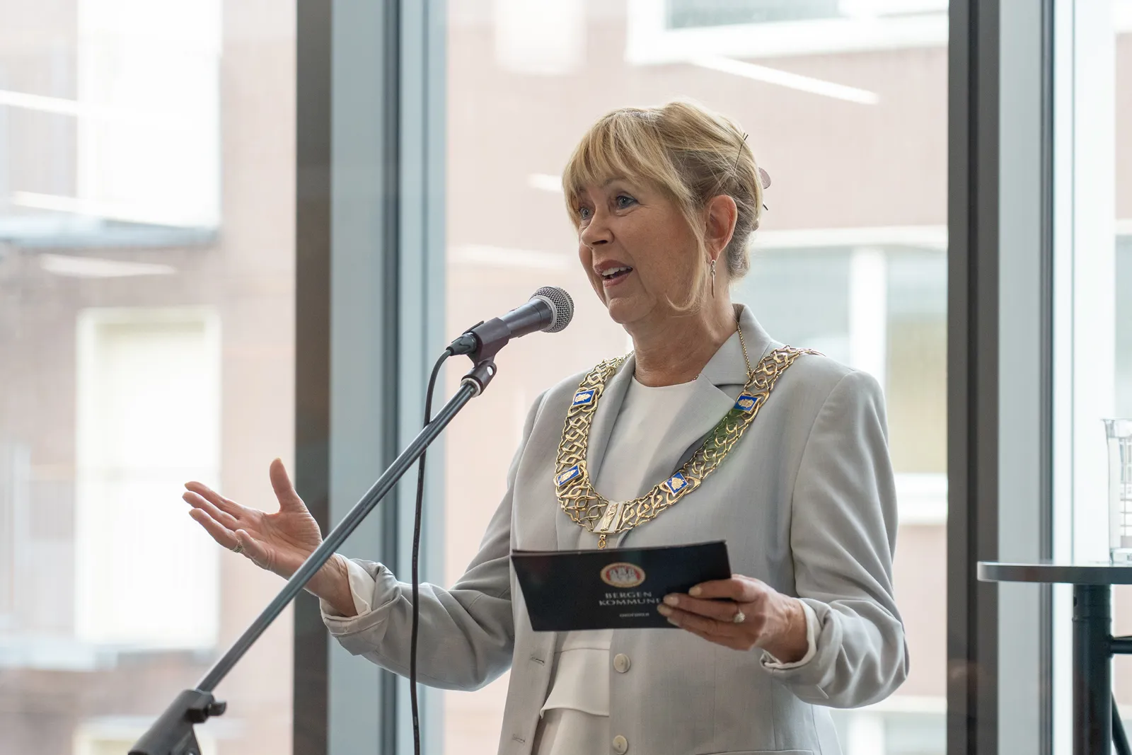 En kvinne med ordførerkjede snakker i en mikrofon