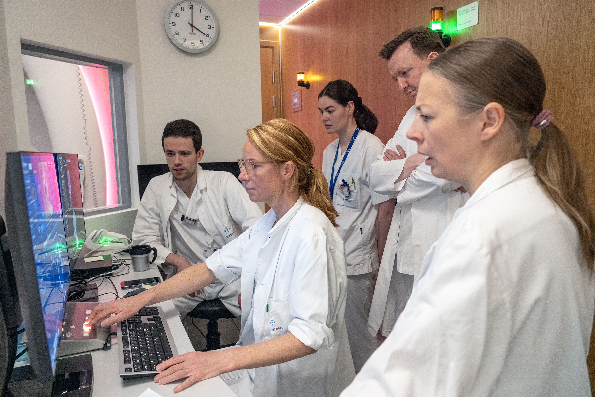 En gruppe mennesker i hvite frakker ser på en skjerm