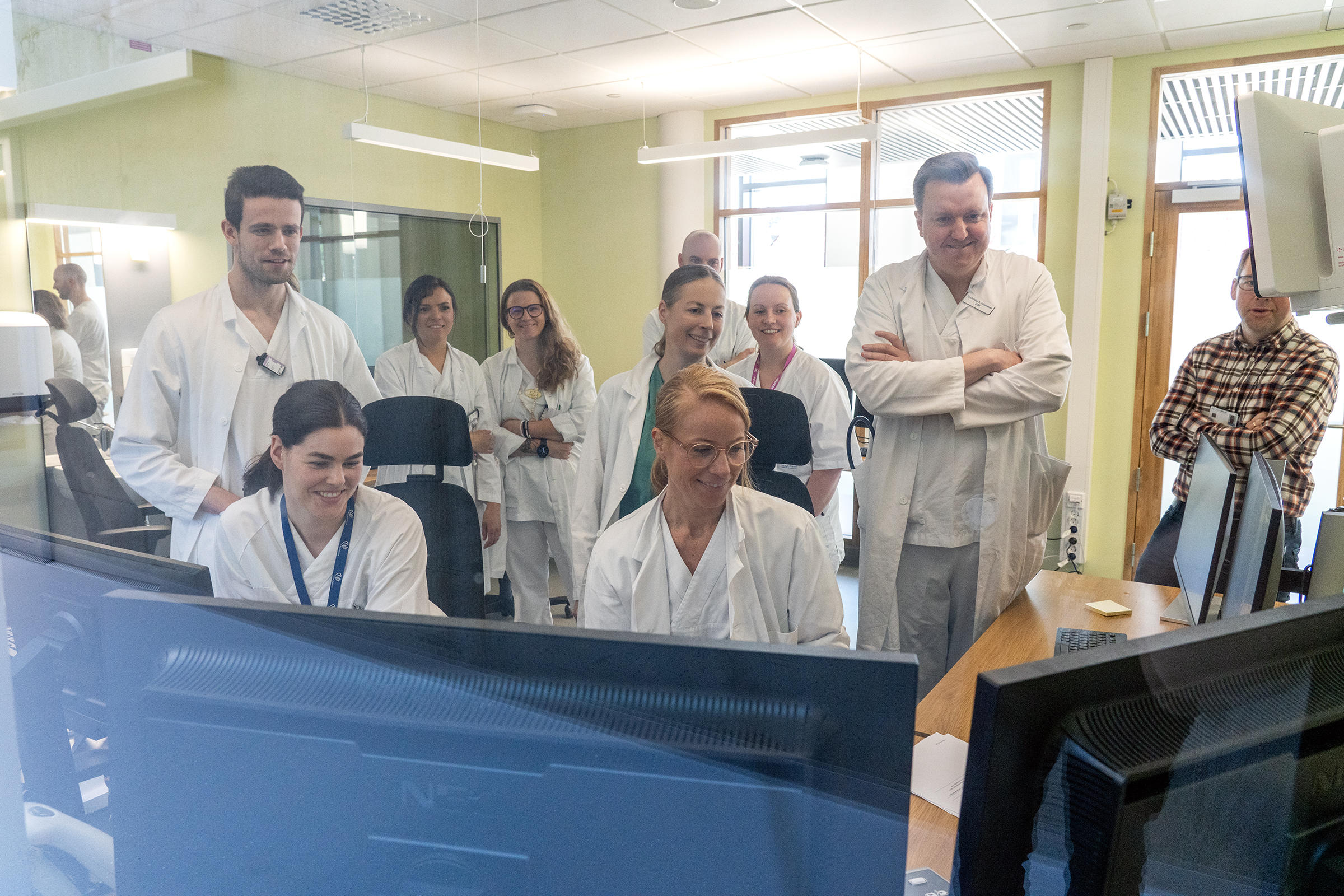 En gruppe mennesker som ser på flere skjermer