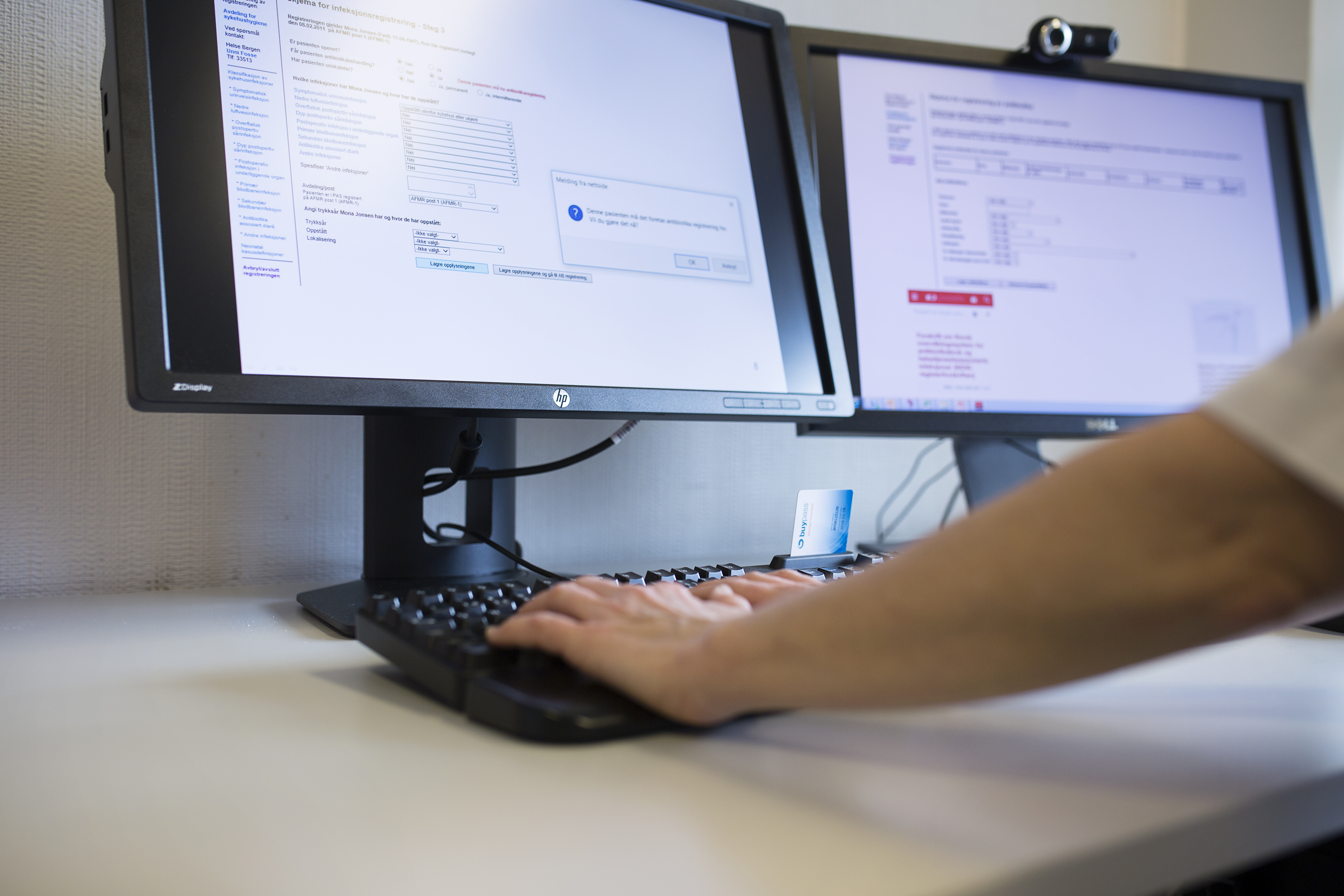 To dataskjermer og hender som skriver på et tastatur
