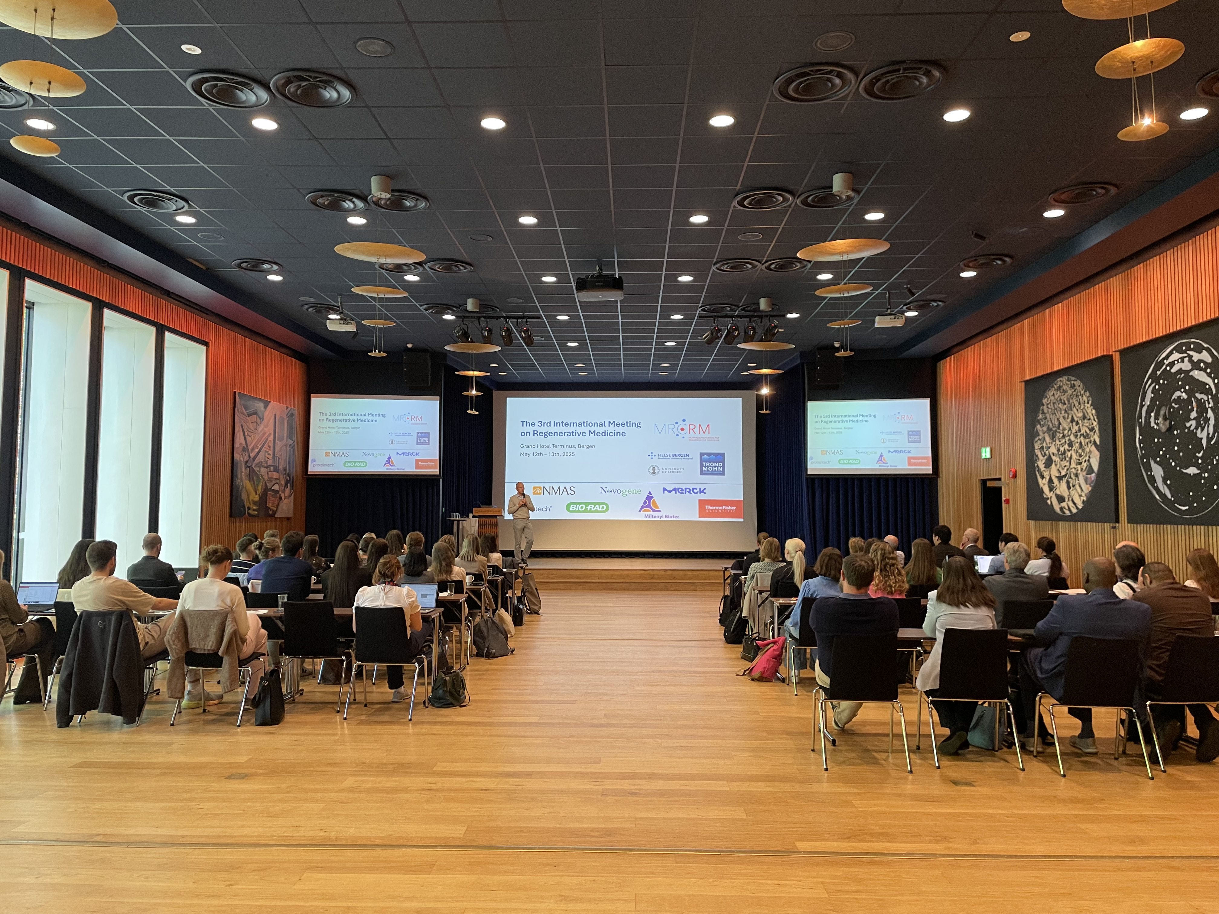 A group of people sitting in a room with a large screen