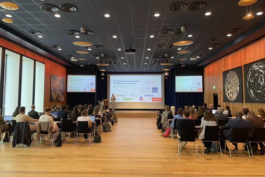 A group of people sitting in a room with a large screen