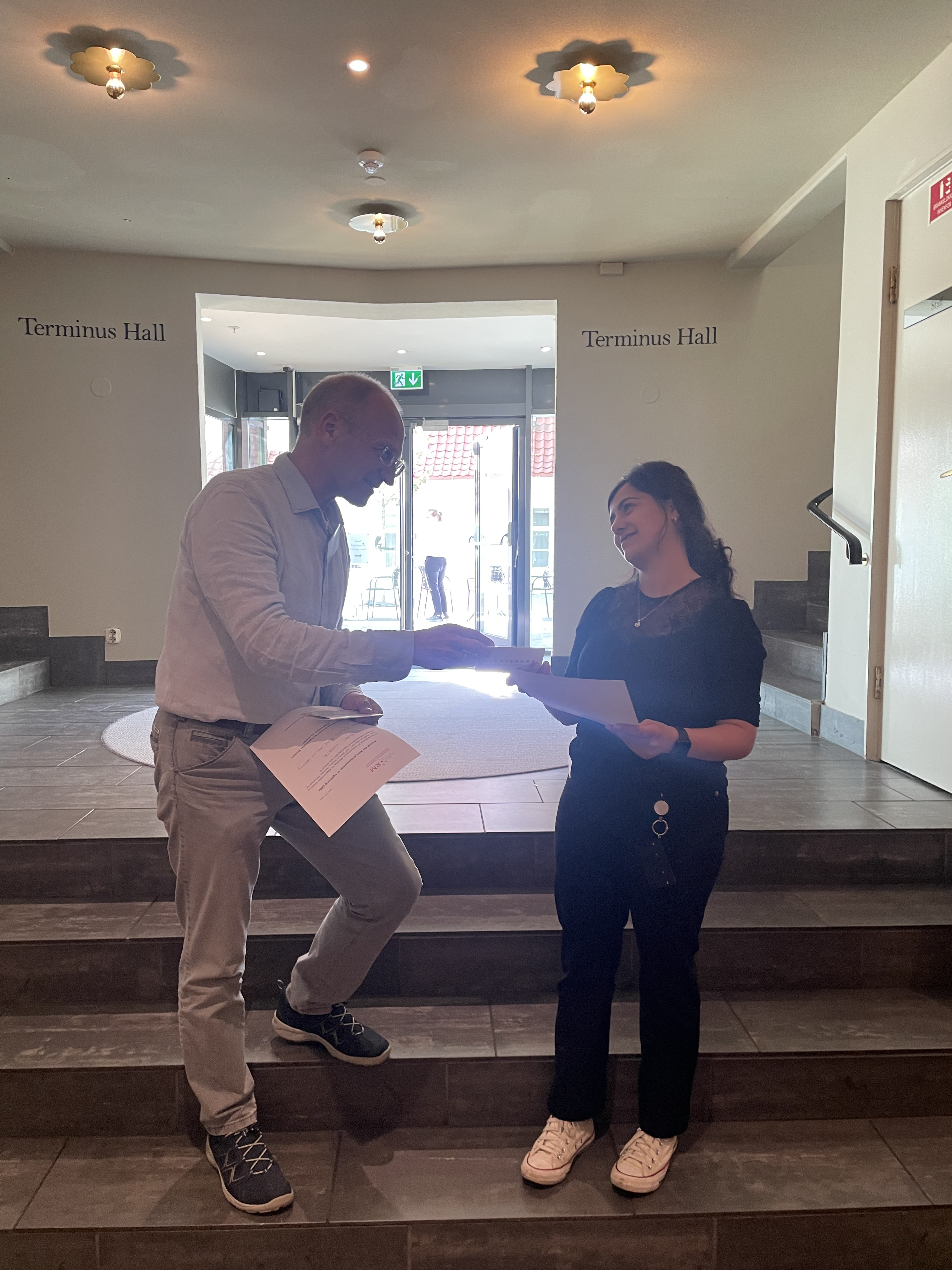 A man and woman standing next to each other and looking at a paper