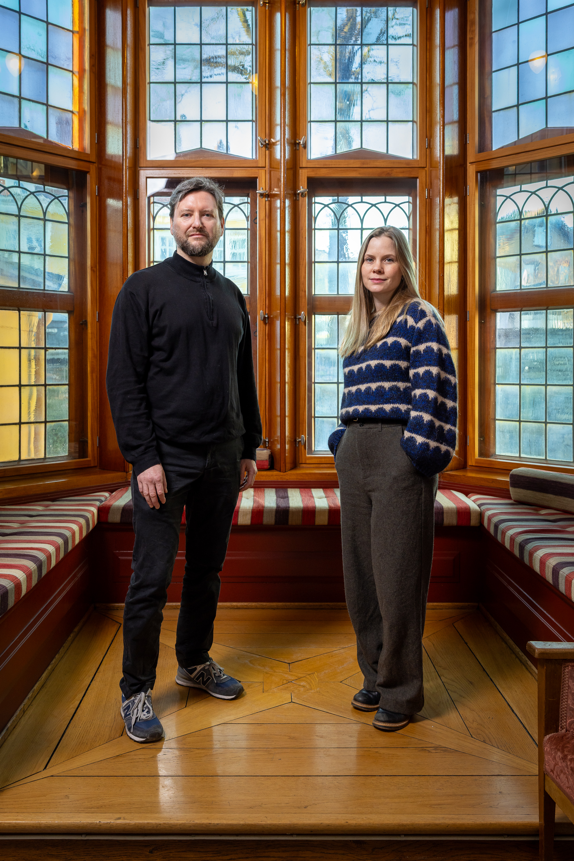A man and woman standing in front of a large window