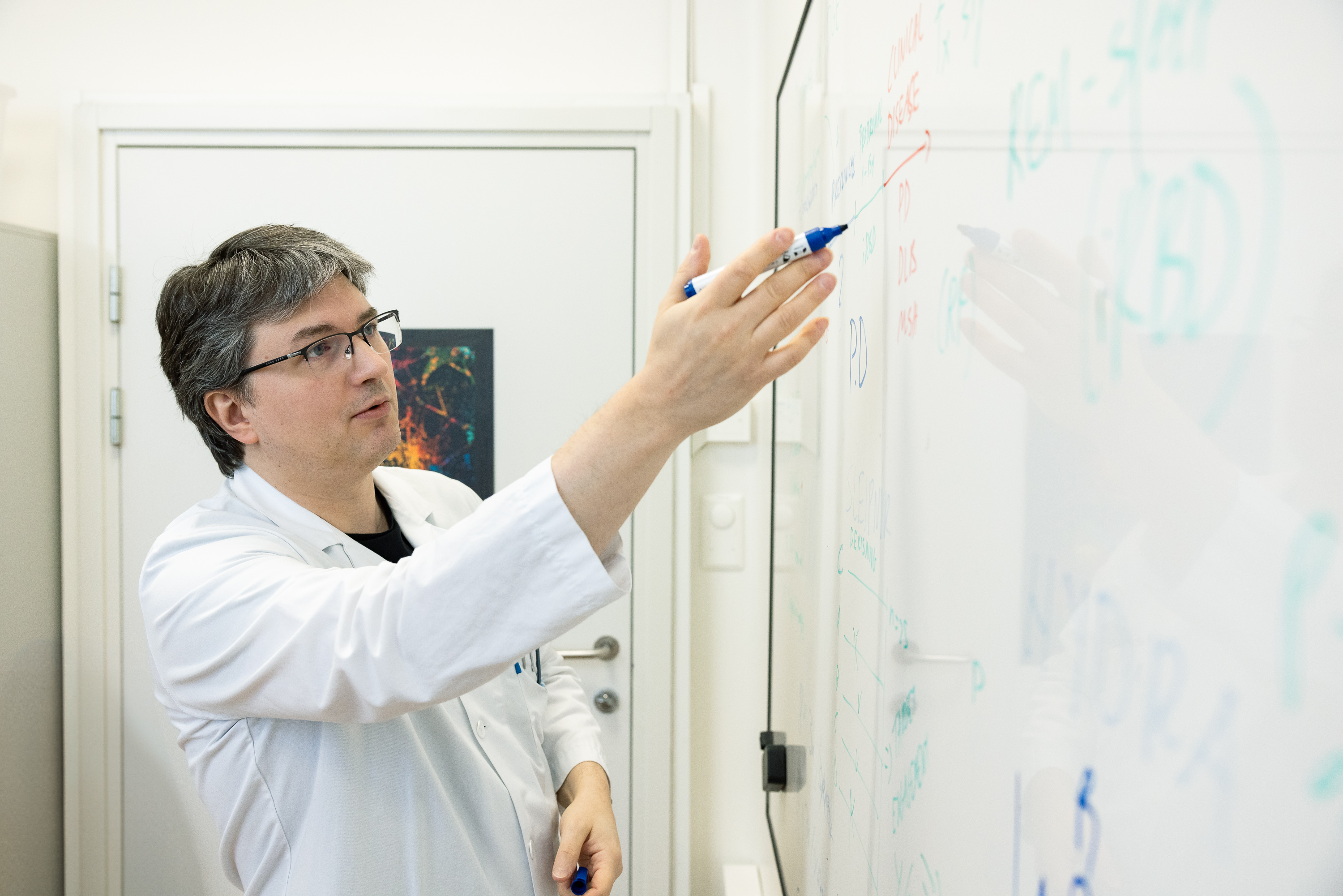 Ein mann i labfrakk som skriv på ei tavle