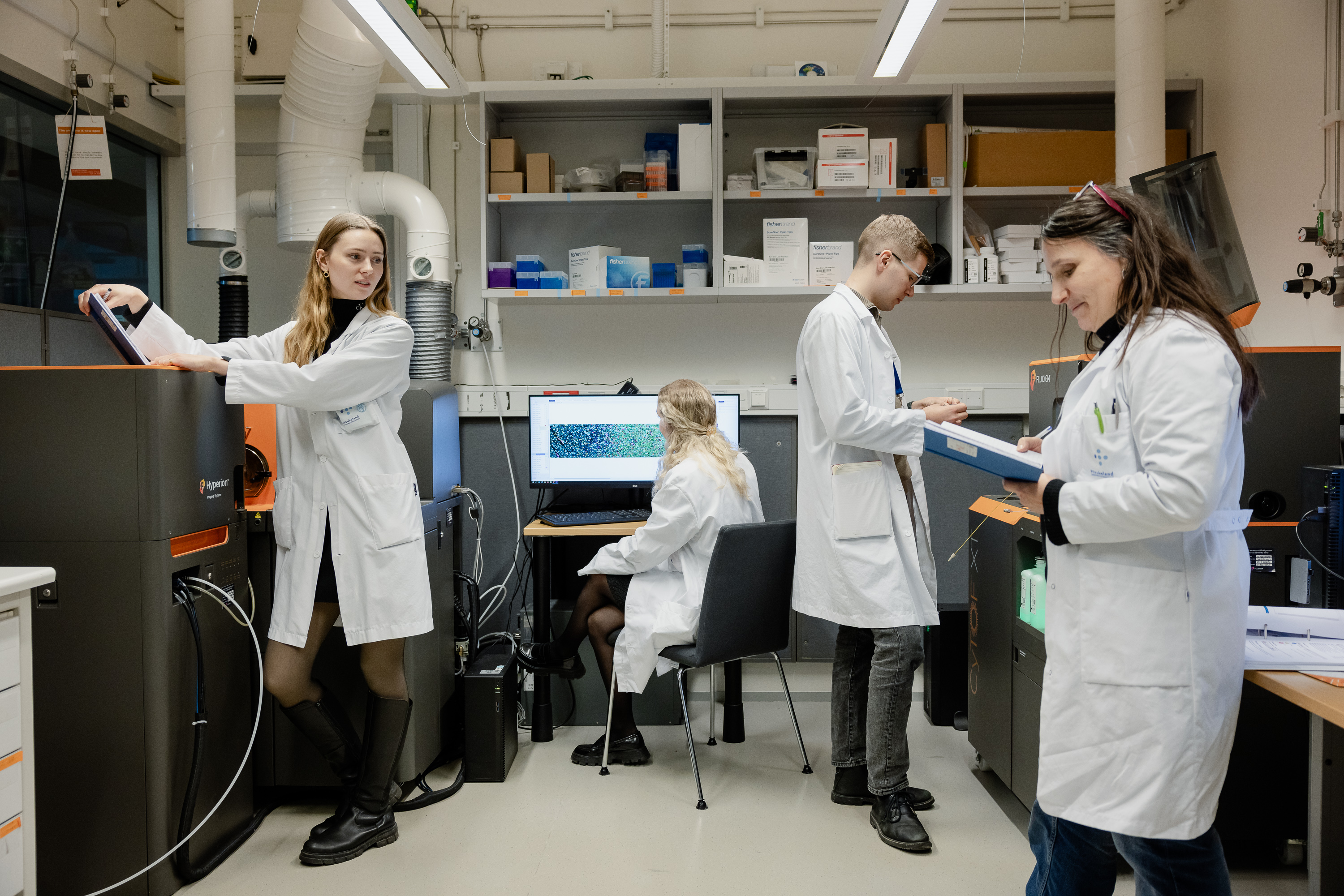 Fire personar i laboratoriefrakkar i konsentrert arbeid i laboratorium.