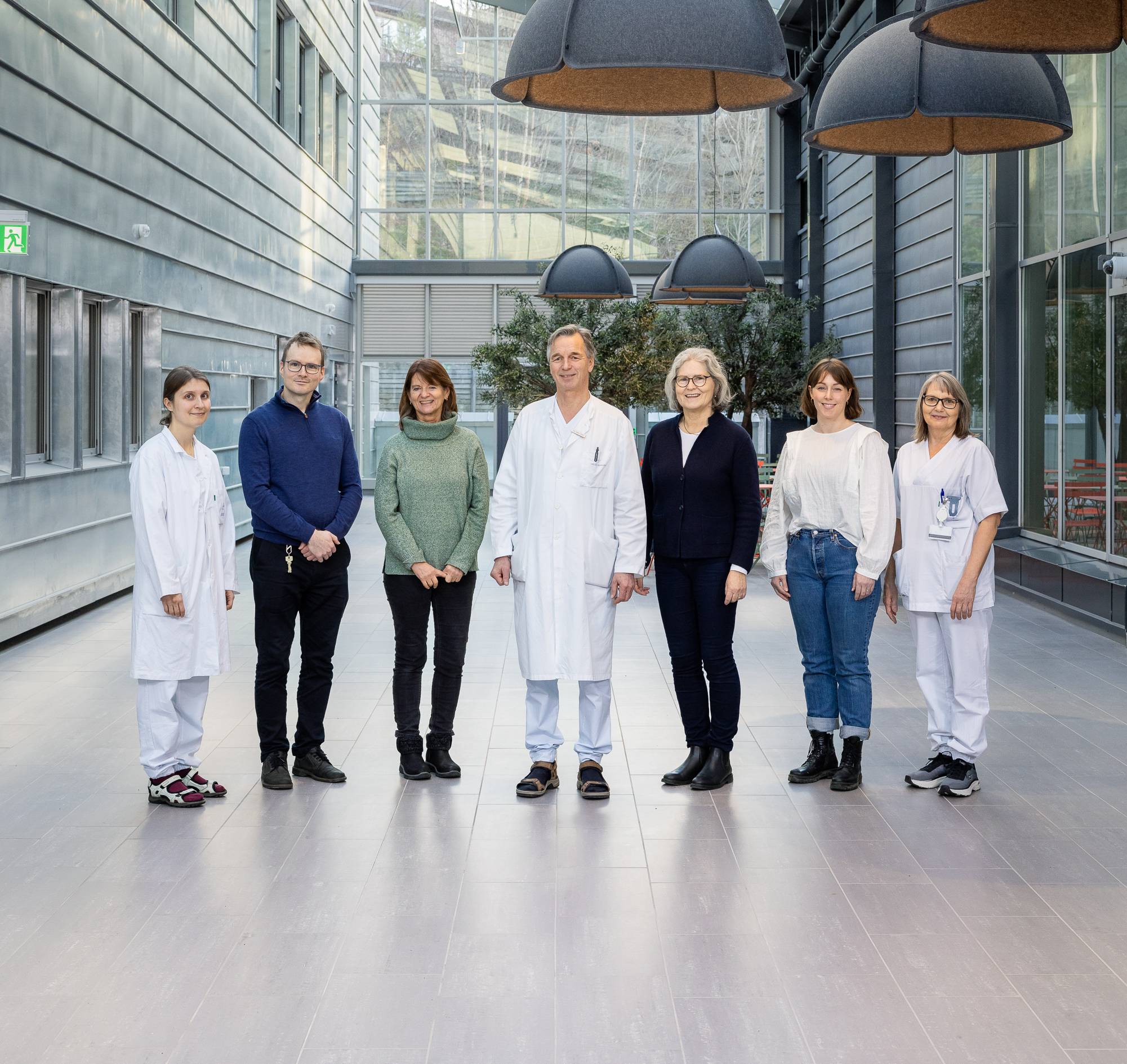 En gruppe mennesker som poserer for et bilde i en moderne glass- og stålbygning