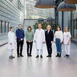 En gruppe mennesker som poserer for et bilde i en moderne glass- og stålbygning