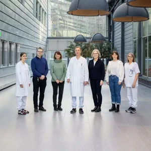 En gruppe mennesker som poserer for et bilde i en moderne glass- og stålbygning