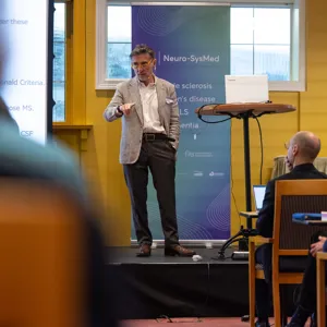 Xavier Montalban står foran et podium med en mikrofon med publikum foran seg