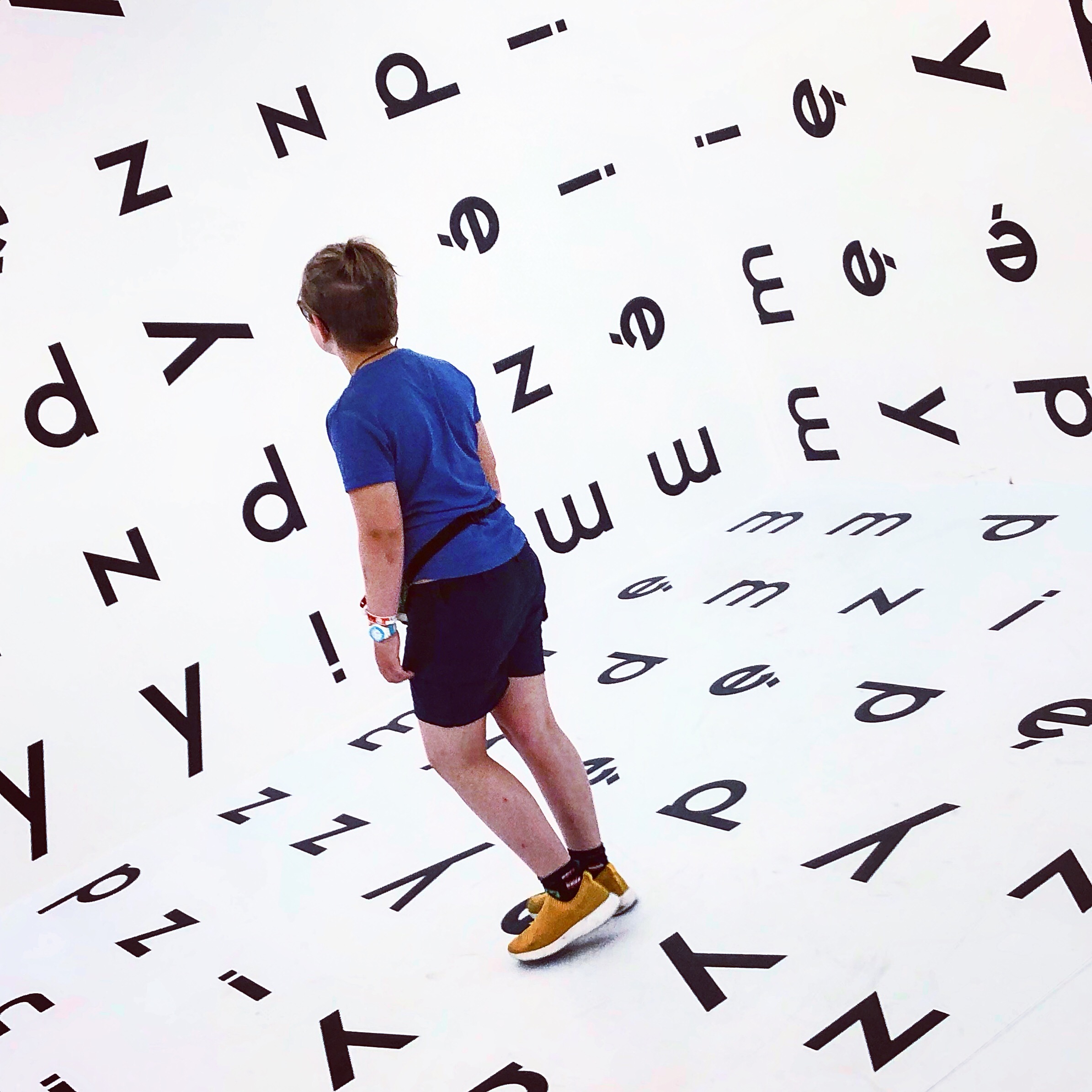 Et barn i et rom med bokstaver på veggene.