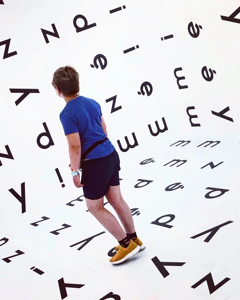 Et barn i et rom med bokstaver på veggene.