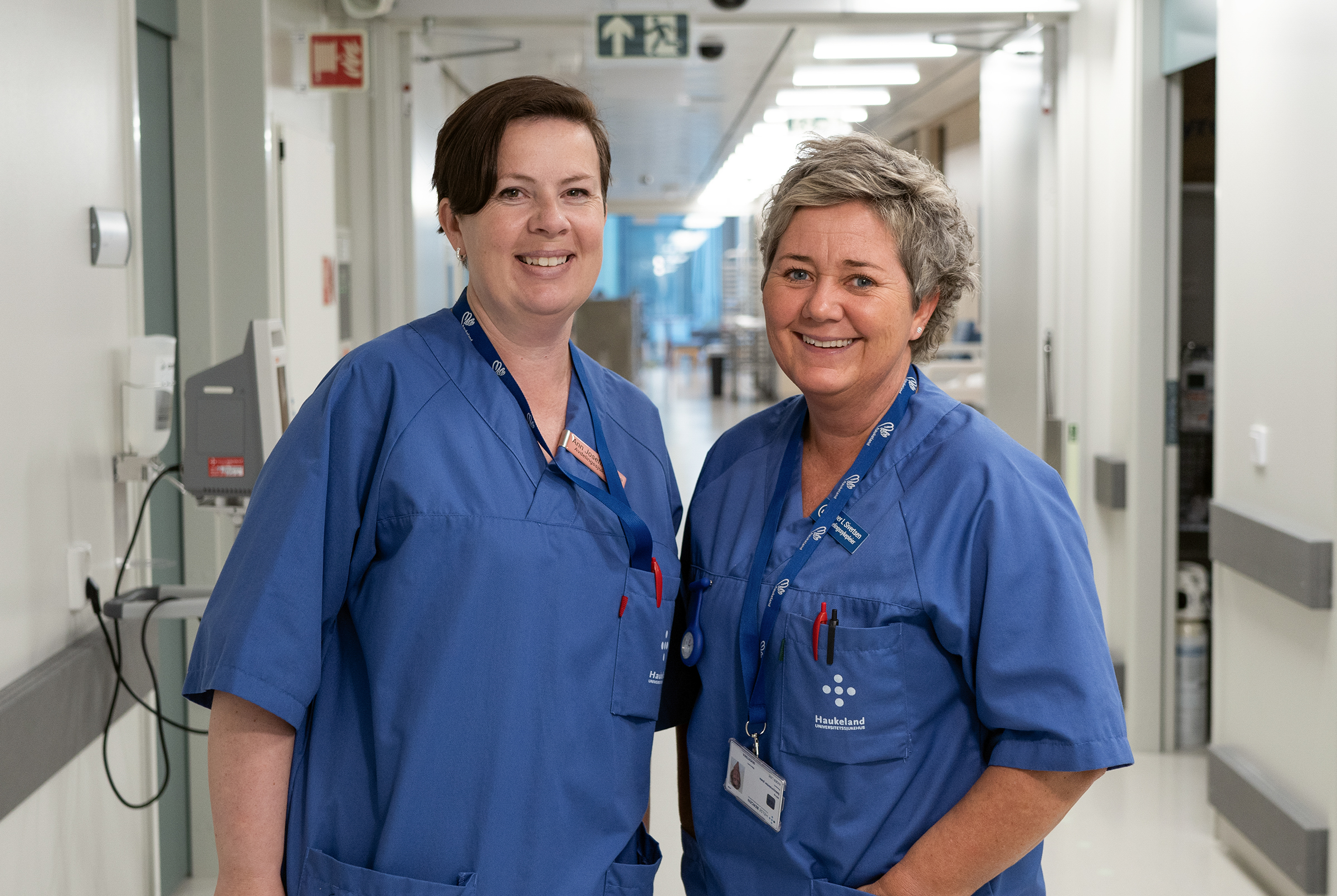 Two women wearing blue shirts in a hospital hallway
