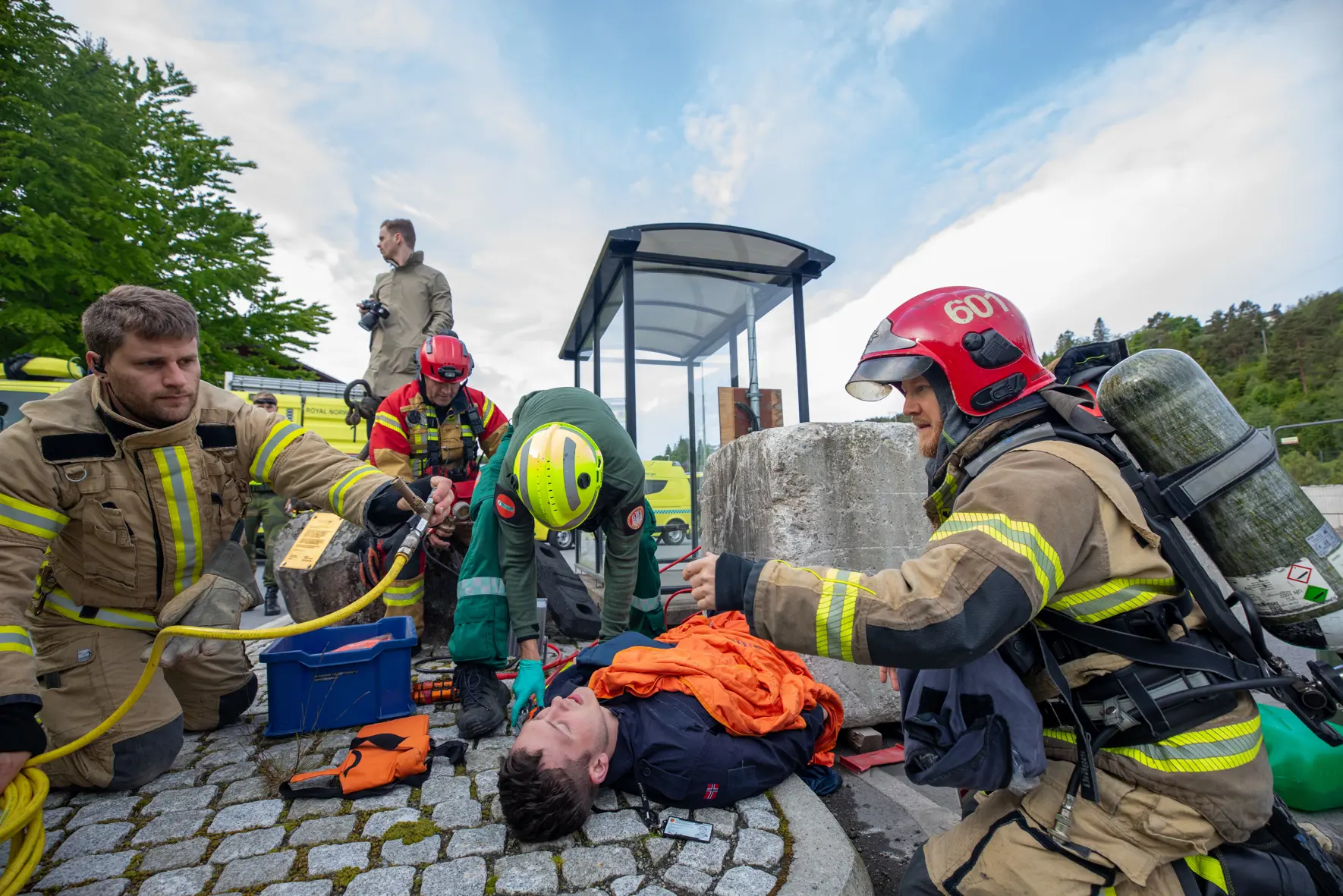Brannvesen, politi og helsepersonell tar seg av en skadet person.