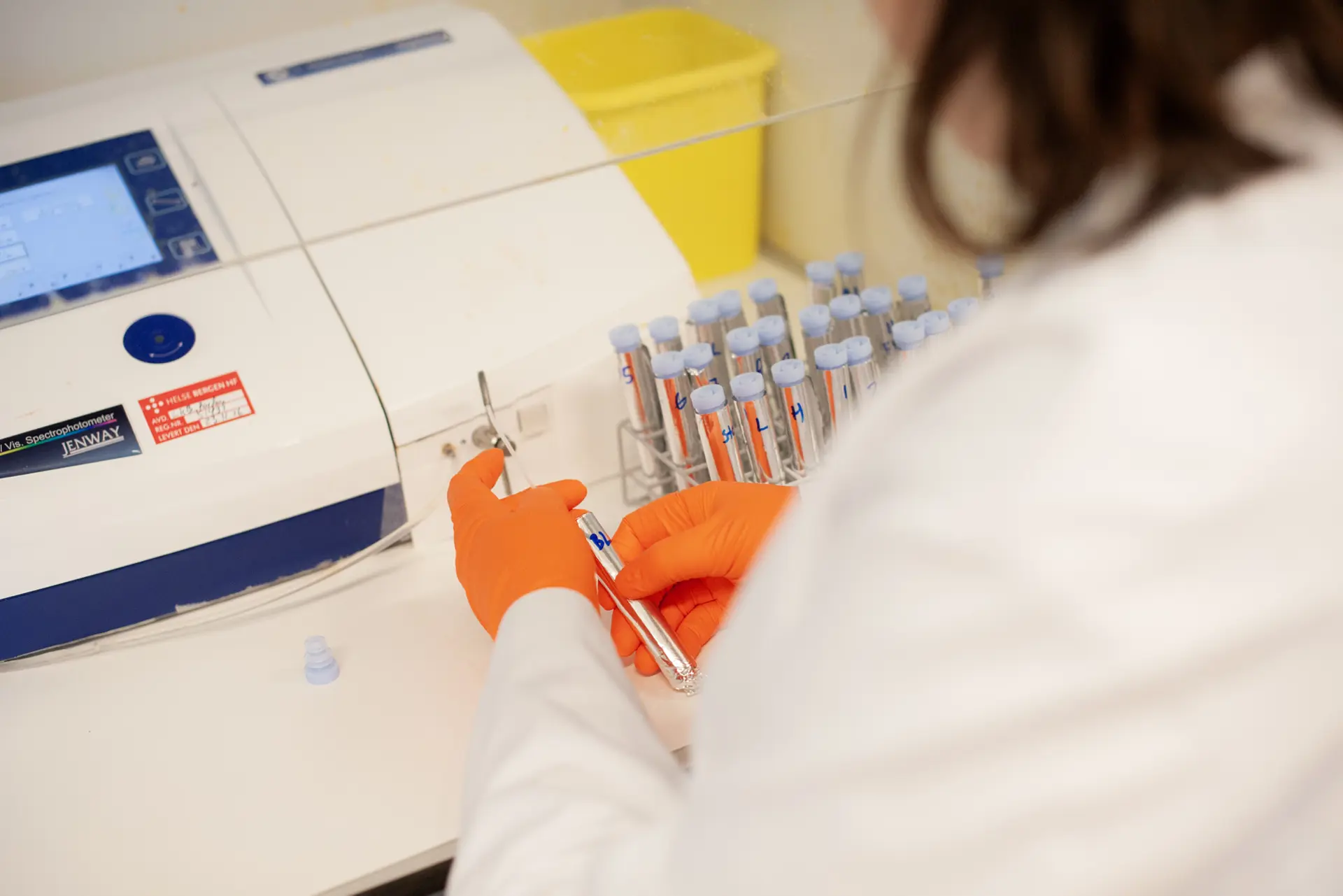 En person i hvit laboratoriefrakk som holder i et reagensrør