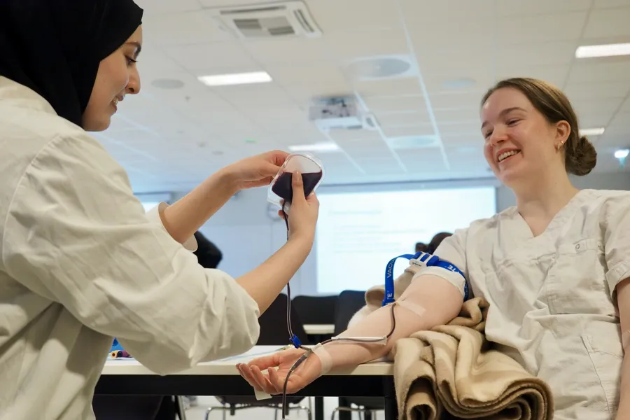 A woman draws blood from the arm of another woman.