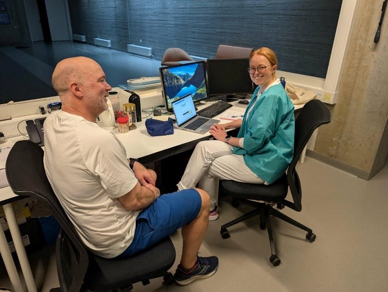 En mann og en kvinne sitter ved et bord med datamaskiner