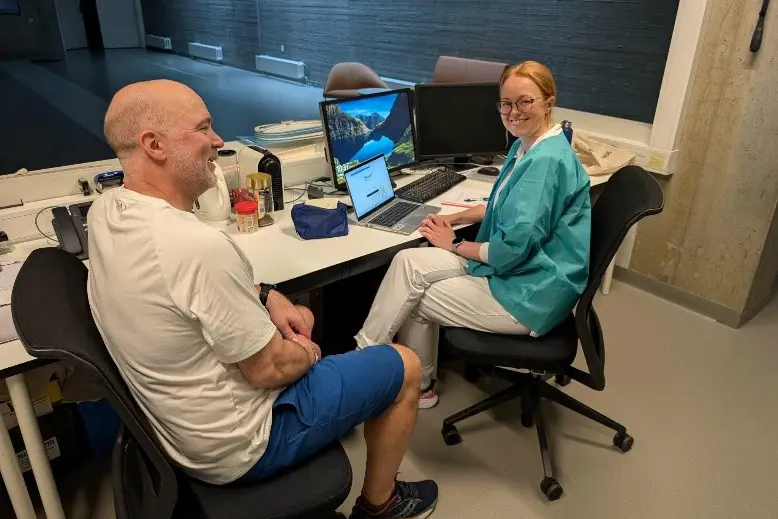 En mann og en kvinne sitter ved et bord med datamaskiner