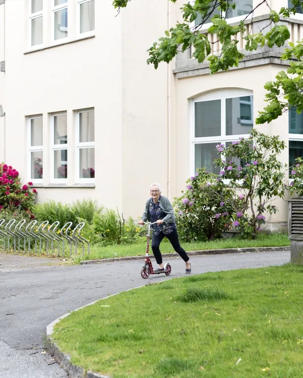 kvinne på sparkesykkel i en park