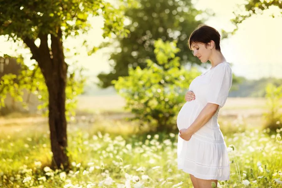 Gravid kvinne som står i en blomstereng.