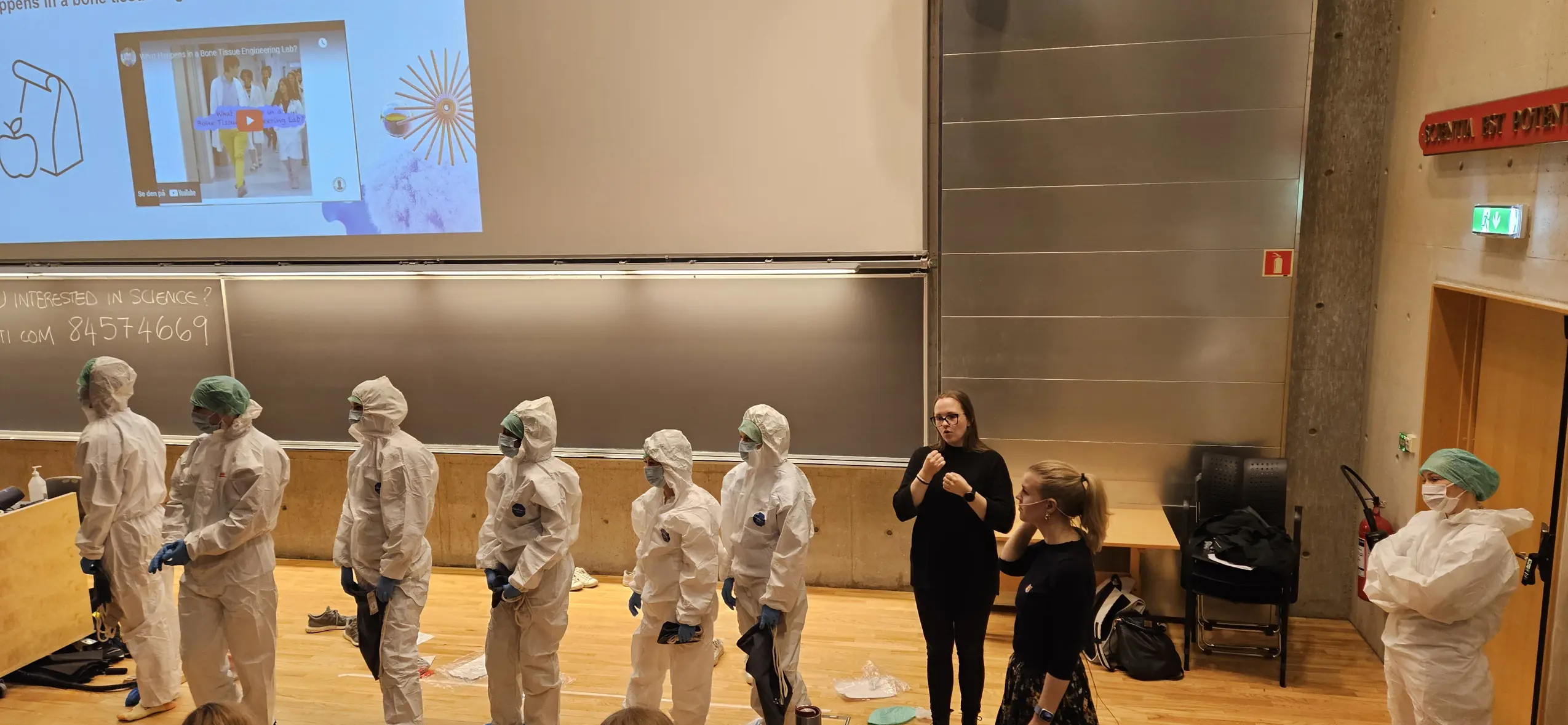 A person standing in front of a group of people in white suits