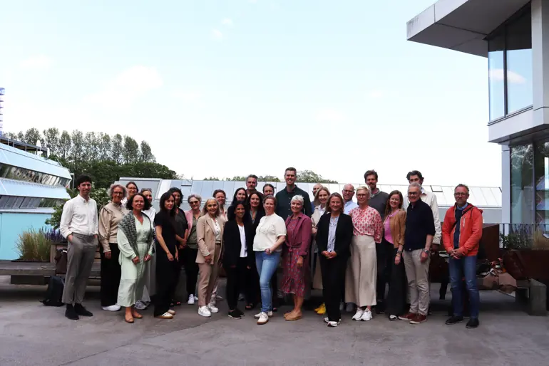 En gruppe mennesker som poserer for et bilde utenfor en bygning