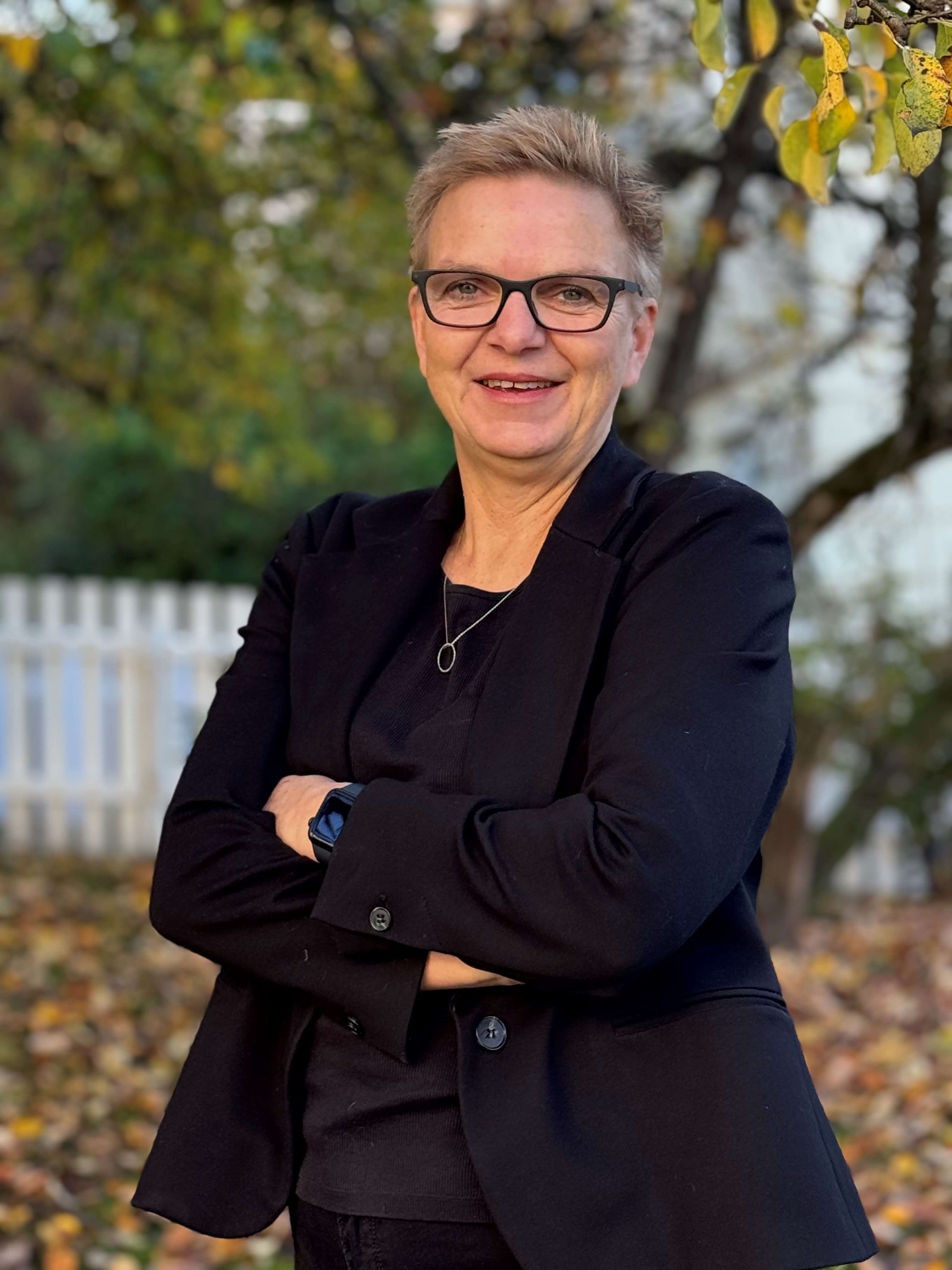 En kvinne som smiler og har armene i kors