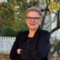 En kvinne som smiler og har armene i kors