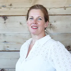 En person som smiler foran en trevegg