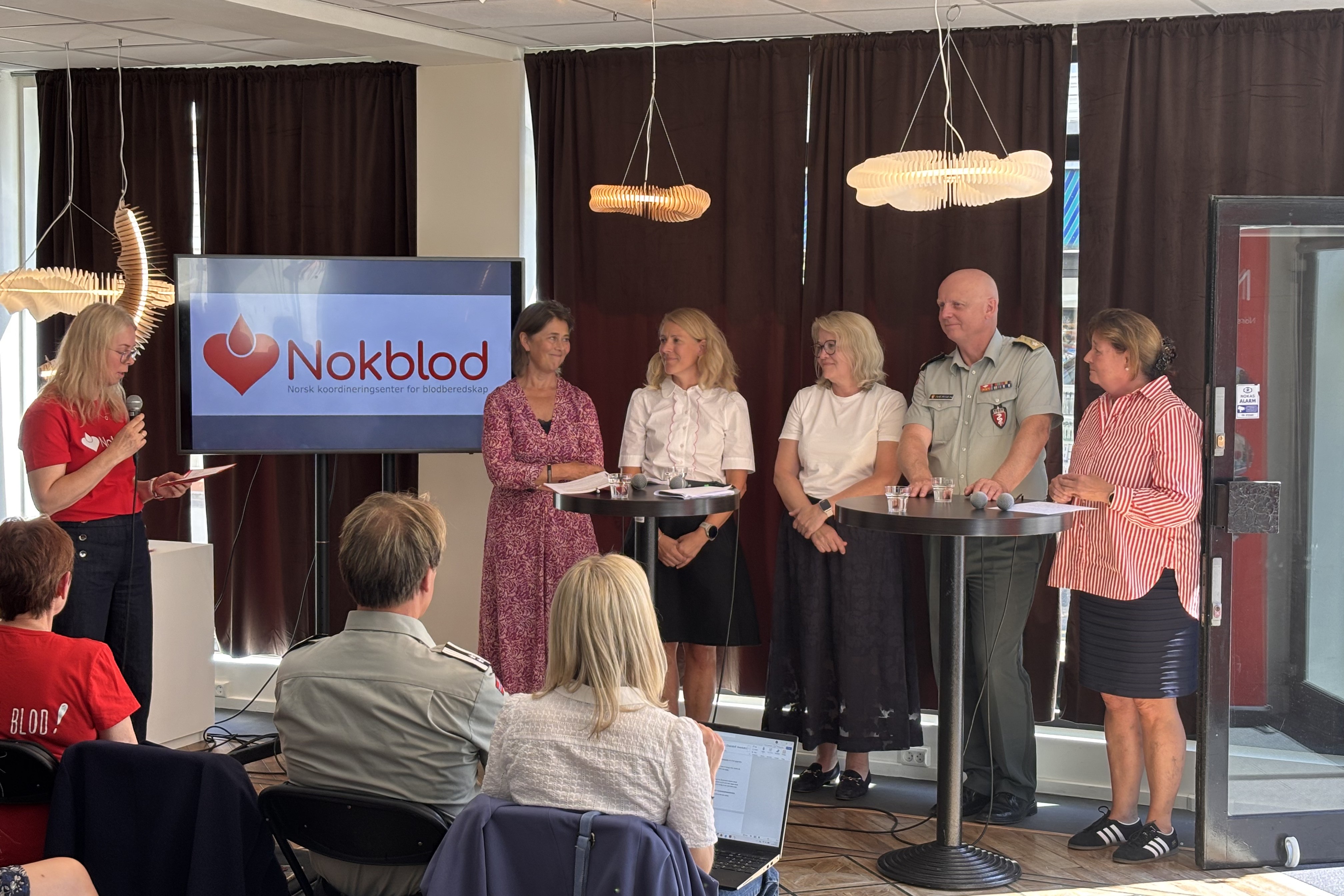 En gruppe mennesker som står foran en talerstol
