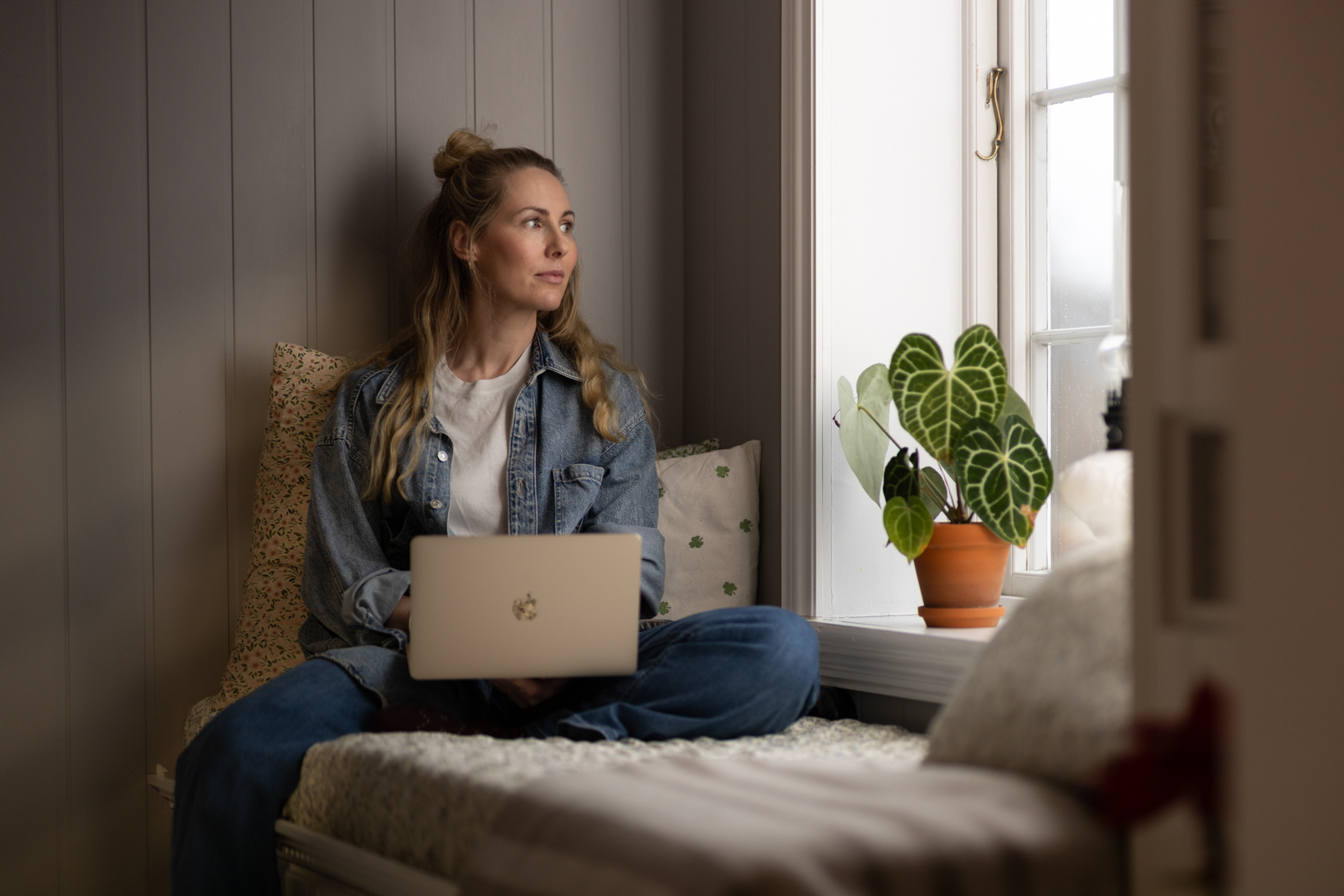 En kvinne som sitter i en sofa med en bærbar PC