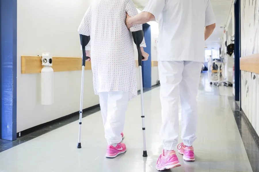 bilde av pasient som støttes av en fysioterapeut i korridor