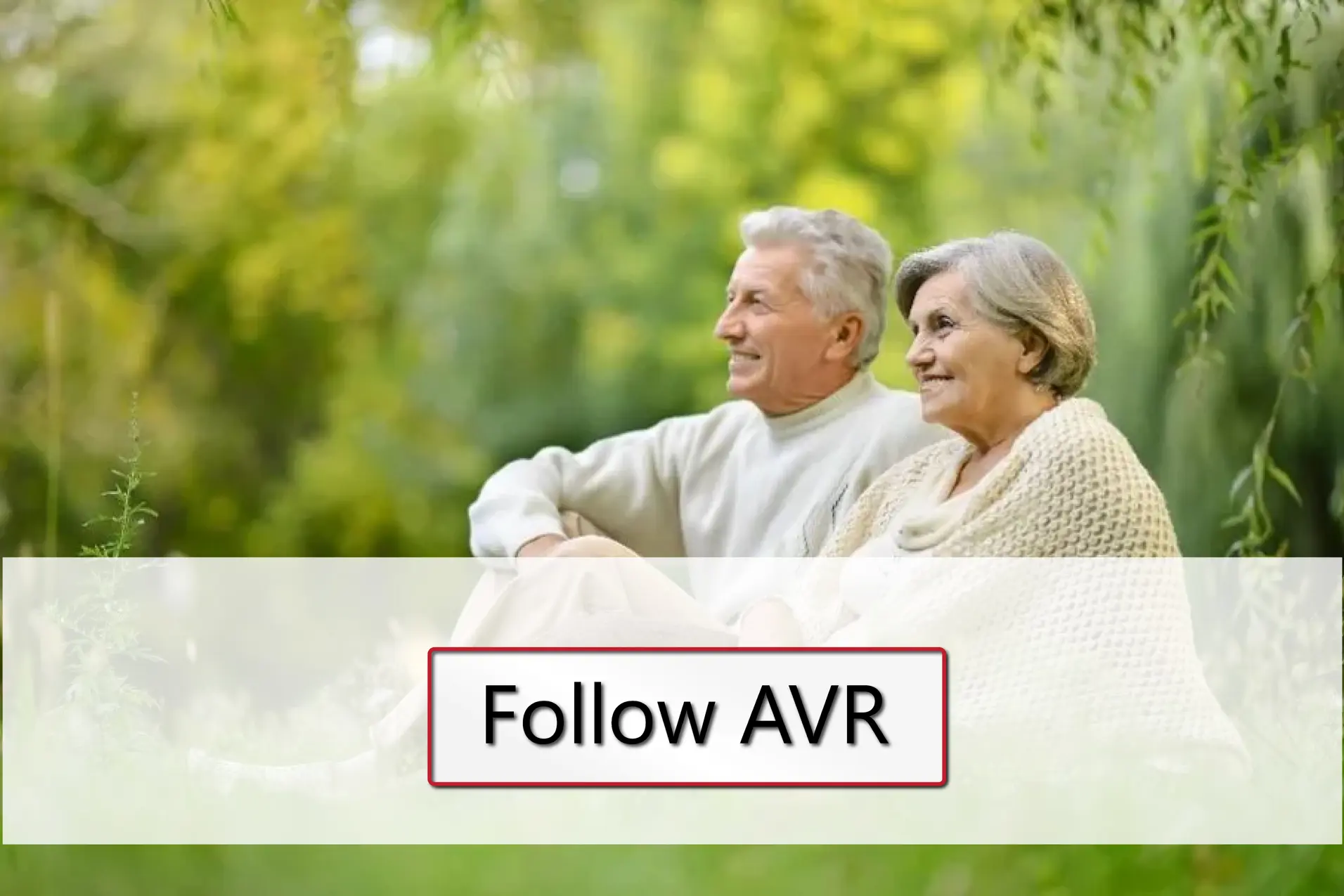 Et eldre par sitter på en plen med skog i bakgrunnen.