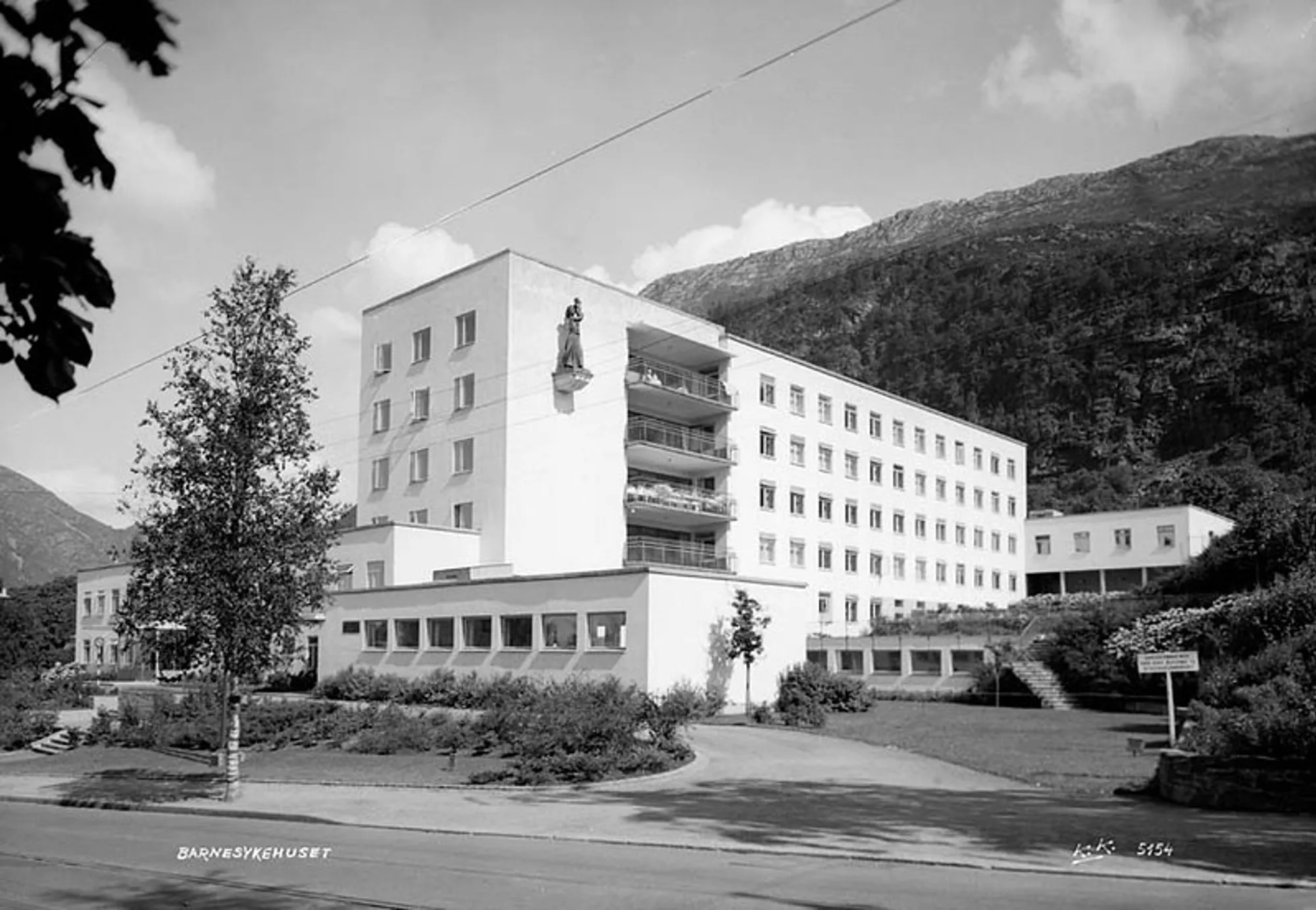 Sort hvitt foto av den gamle barneklinikken med statue hengende på veggen