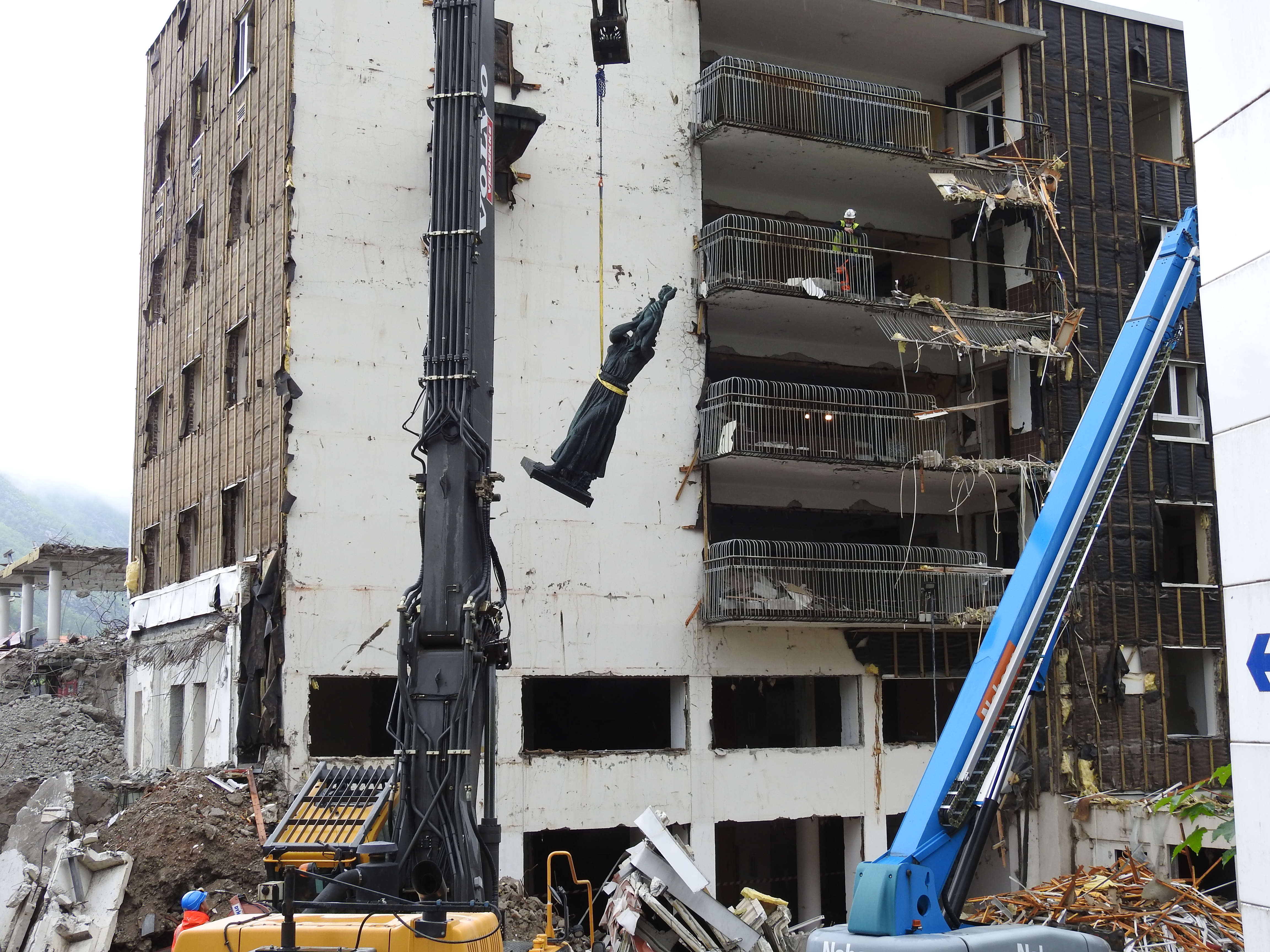 En bygning som rives og en statue heises ned med kran